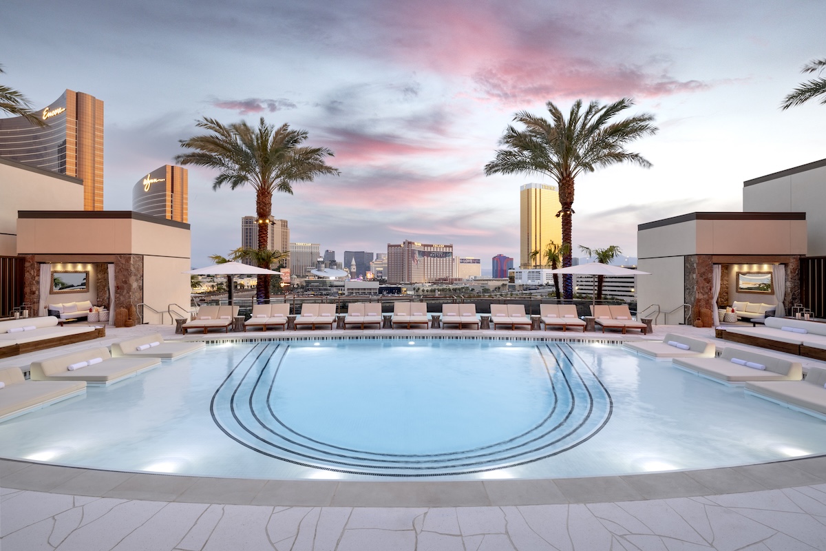 Luxury rooftop pool at a Las Vegas resort with palm trees and lounge chairs at sunset