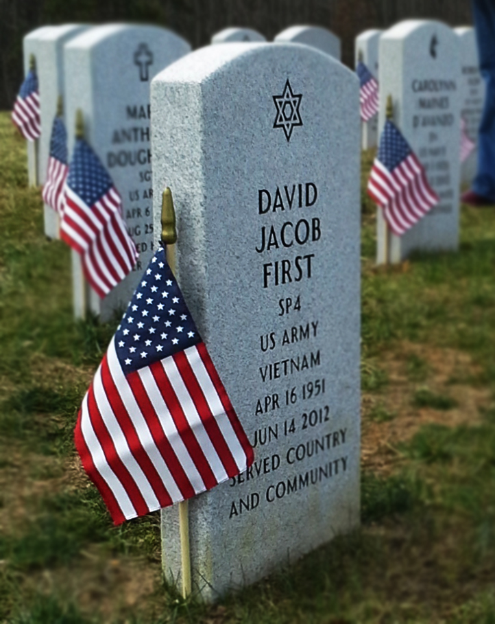 headstones at a cemetery with American flags next to the headstones